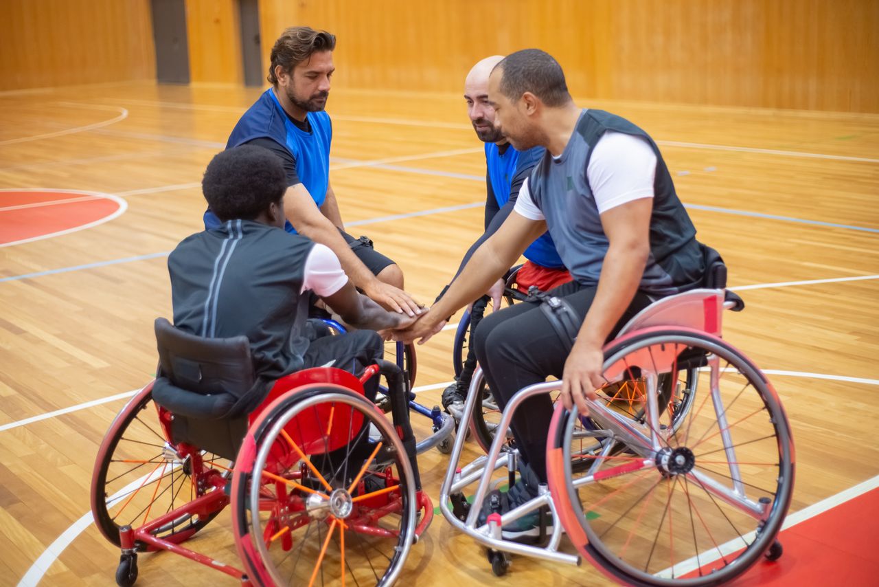 Wheelchair basketball athletes in a team huddle, showing sportsmanship and teamwork.